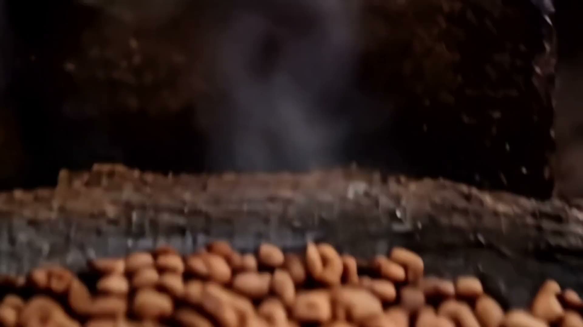 Cacao beans roasting on a clay comal over an open fire, smoke rising